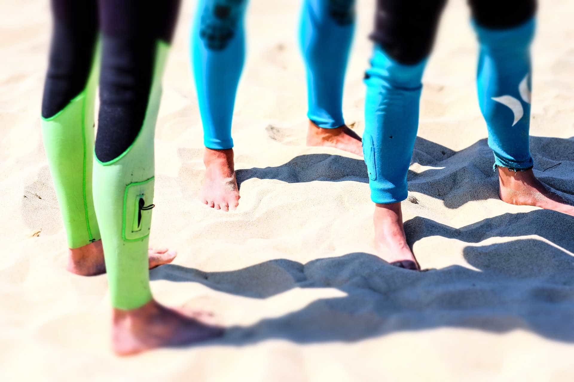 People standing on sandy beach wearing wetsuits