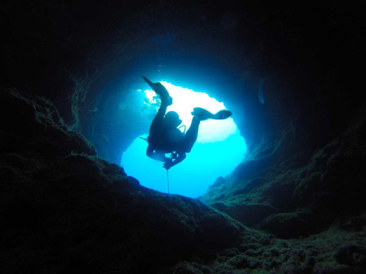 Taucher schwimmt aus Höhle heraus