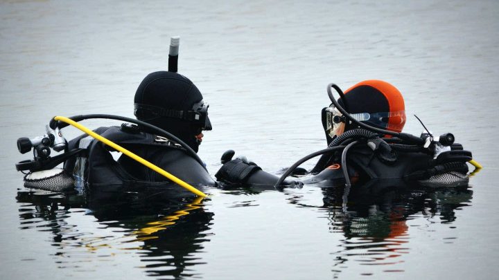Scuba diving instructor in the water with student.