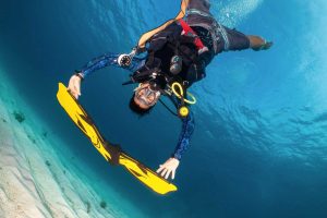 Scuba diving instructor surfing his fins underwater