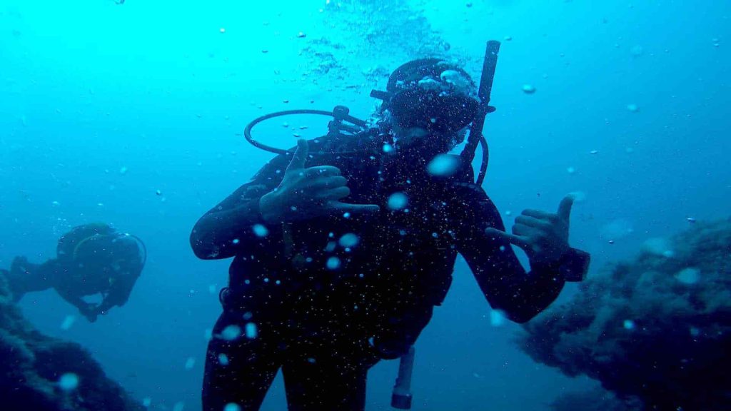 Fröhlicher Taucher macht Blasen unter Wasser