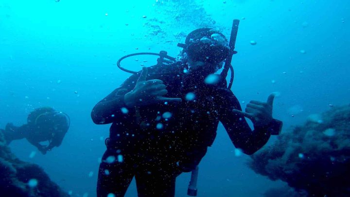 Happy scuba diver making bubbles underwater