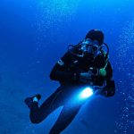 Scuba diver with lamp diving deep
