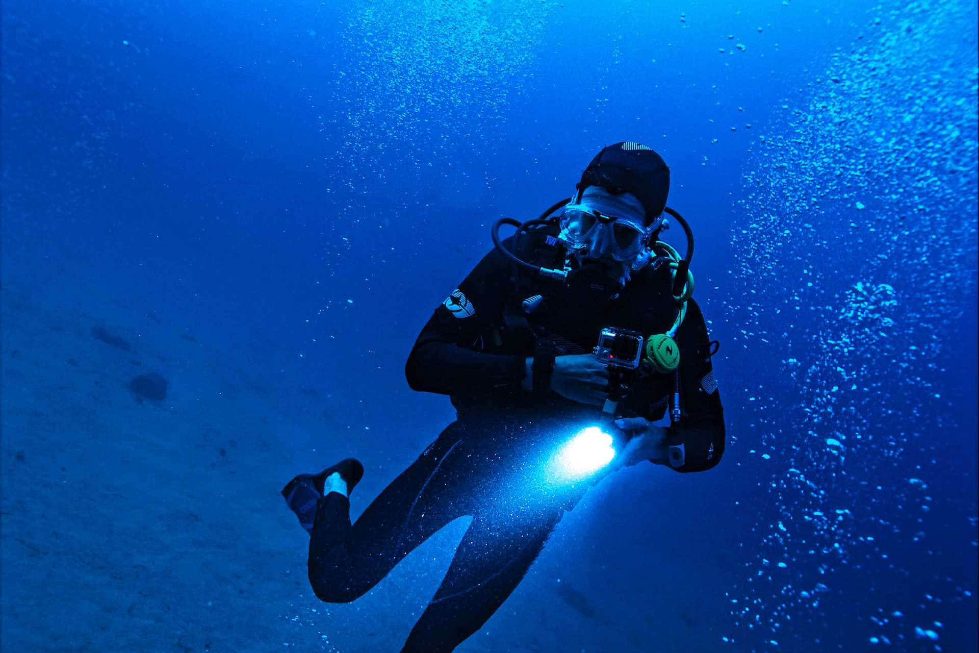 Scuba diver with lamp diving deep