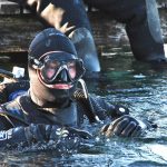 Scuba diver in drysuit diving in lake