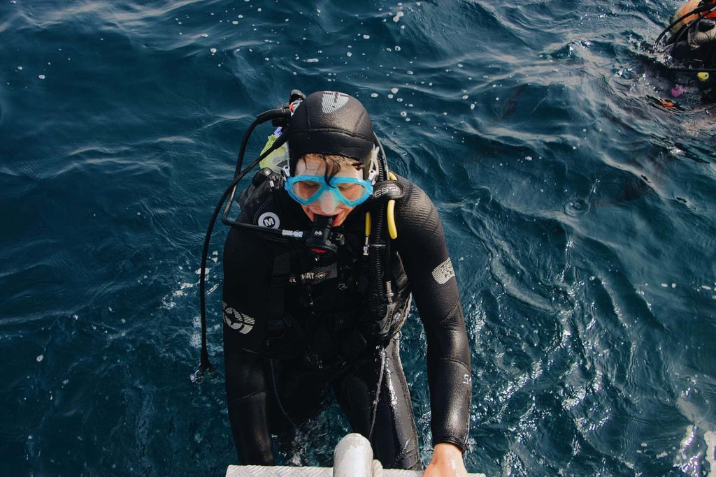 Scuba diver exiting water over ladder