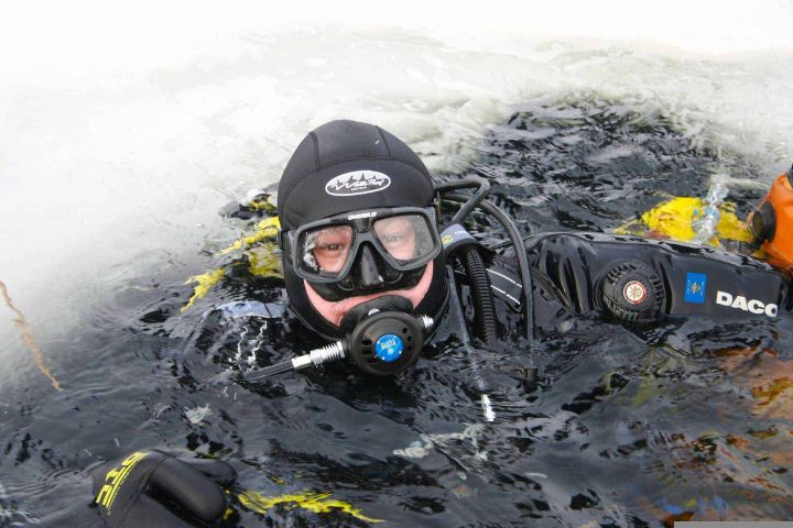 Scuba diver at water surface in ice hole