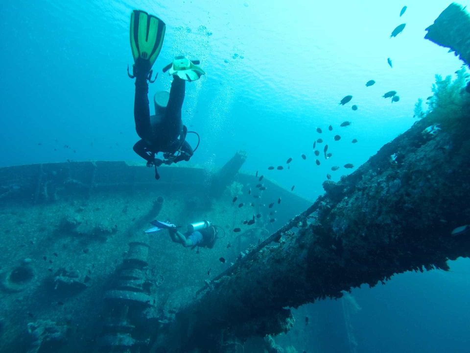 Scuba divers descending down to wreck