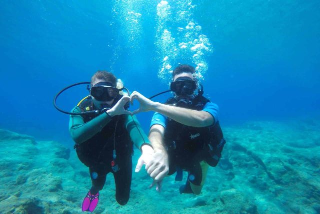 Scuba divers making heart with their hands underwater