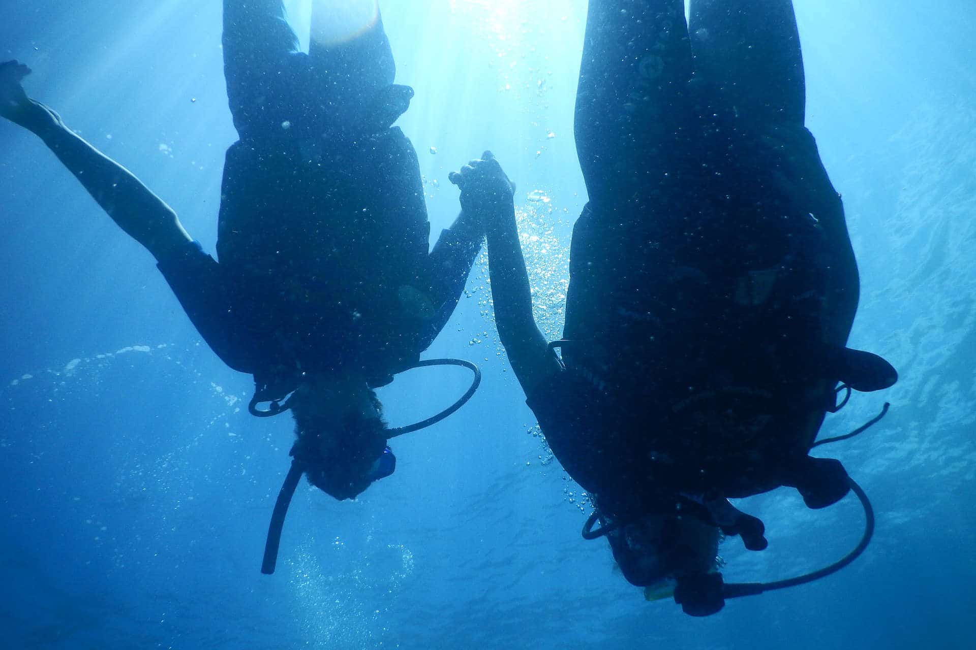 Scuba divers holding hands underwater