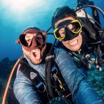 Scuba divers smile into camera