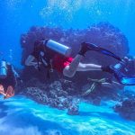 Scuba divers around underwater rock
