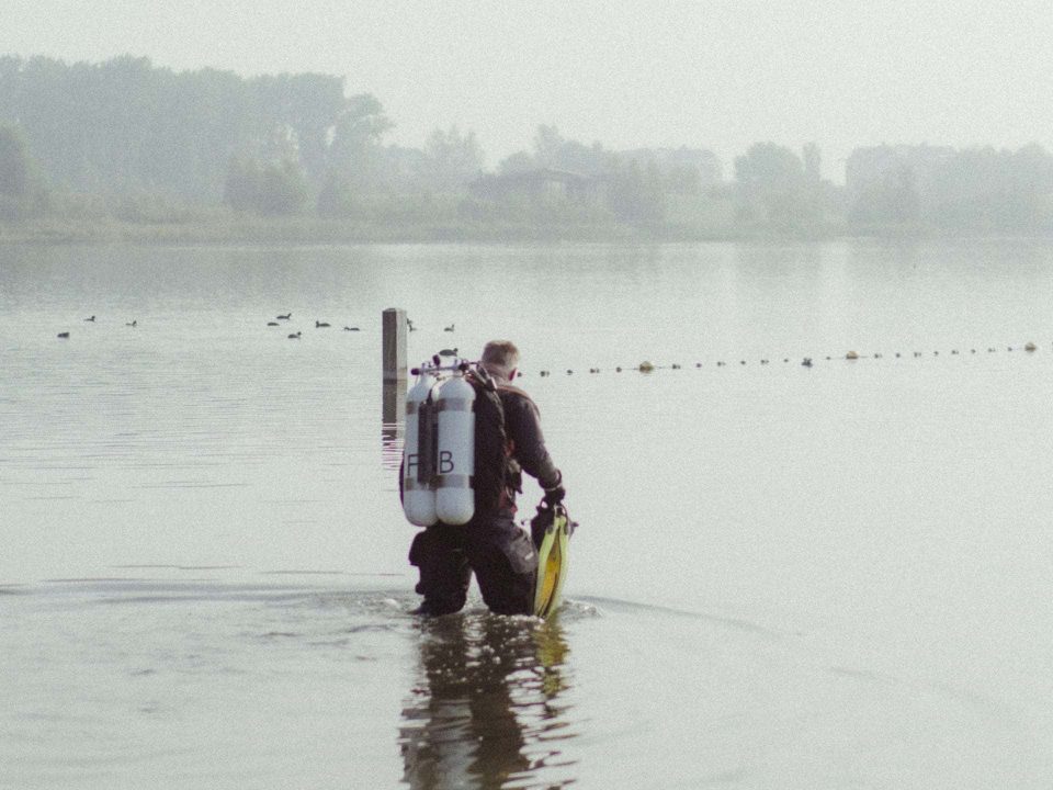 Taucher mit Doppelgerät läuft ins Wasser