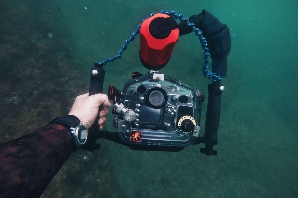 Hand holding underwater camera inside housing