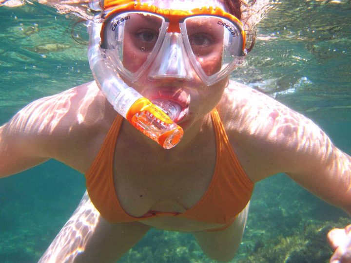 Woman snorkeling with orange snorkel, mask and swim suit