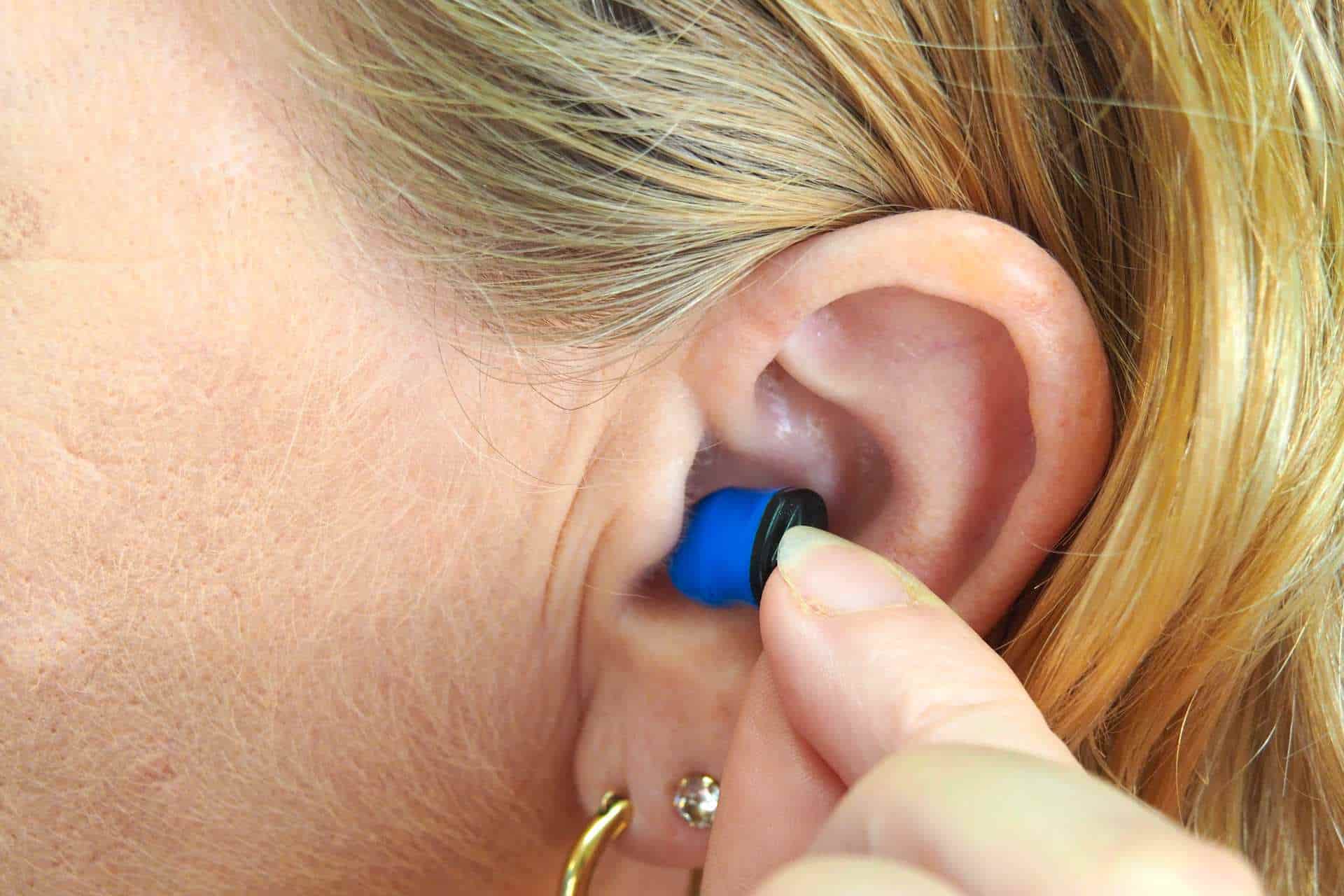 Woman putting earplug into ear.
